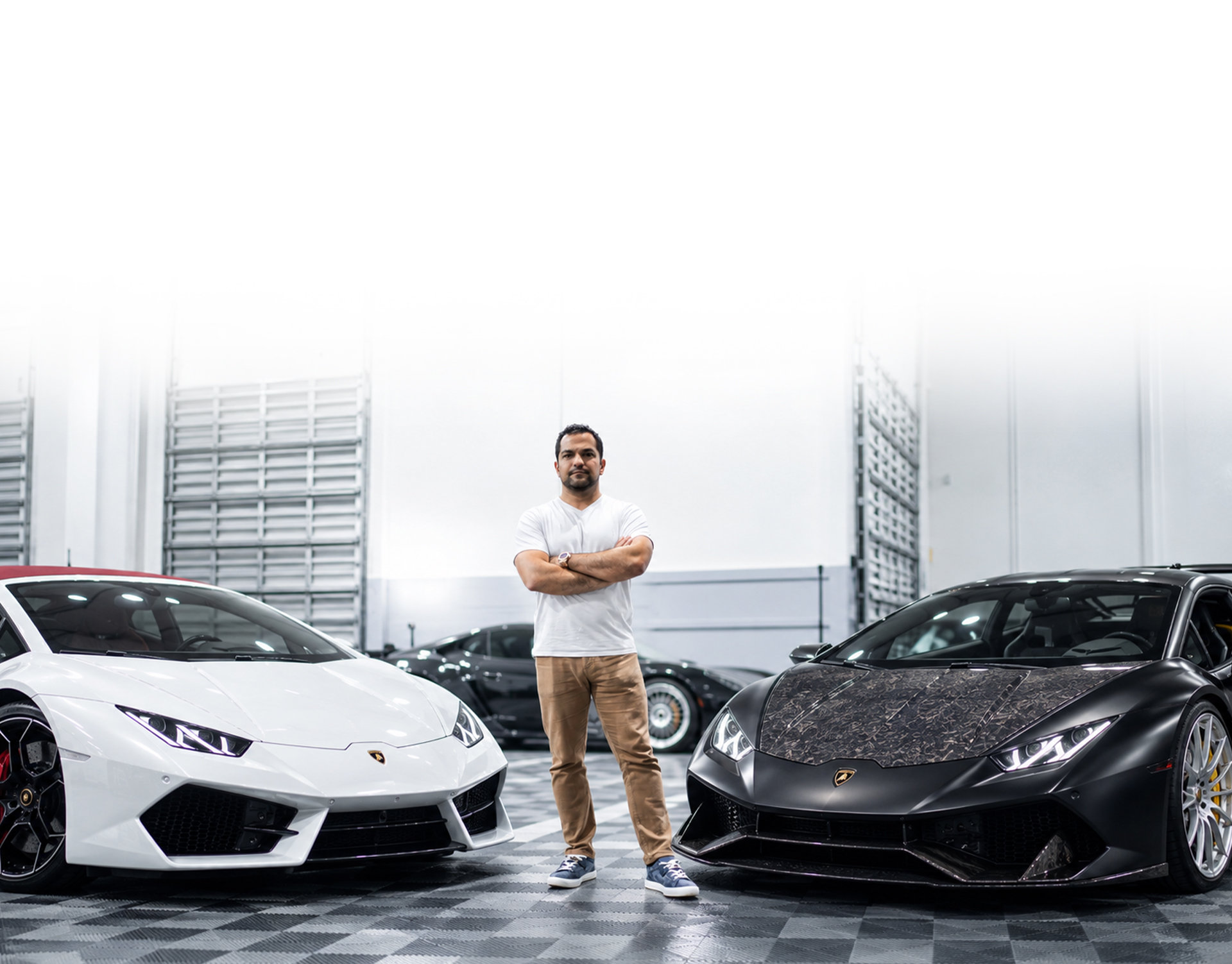 Pejman Ghadimi standing between a white and a matte black Lamborghini Huracán